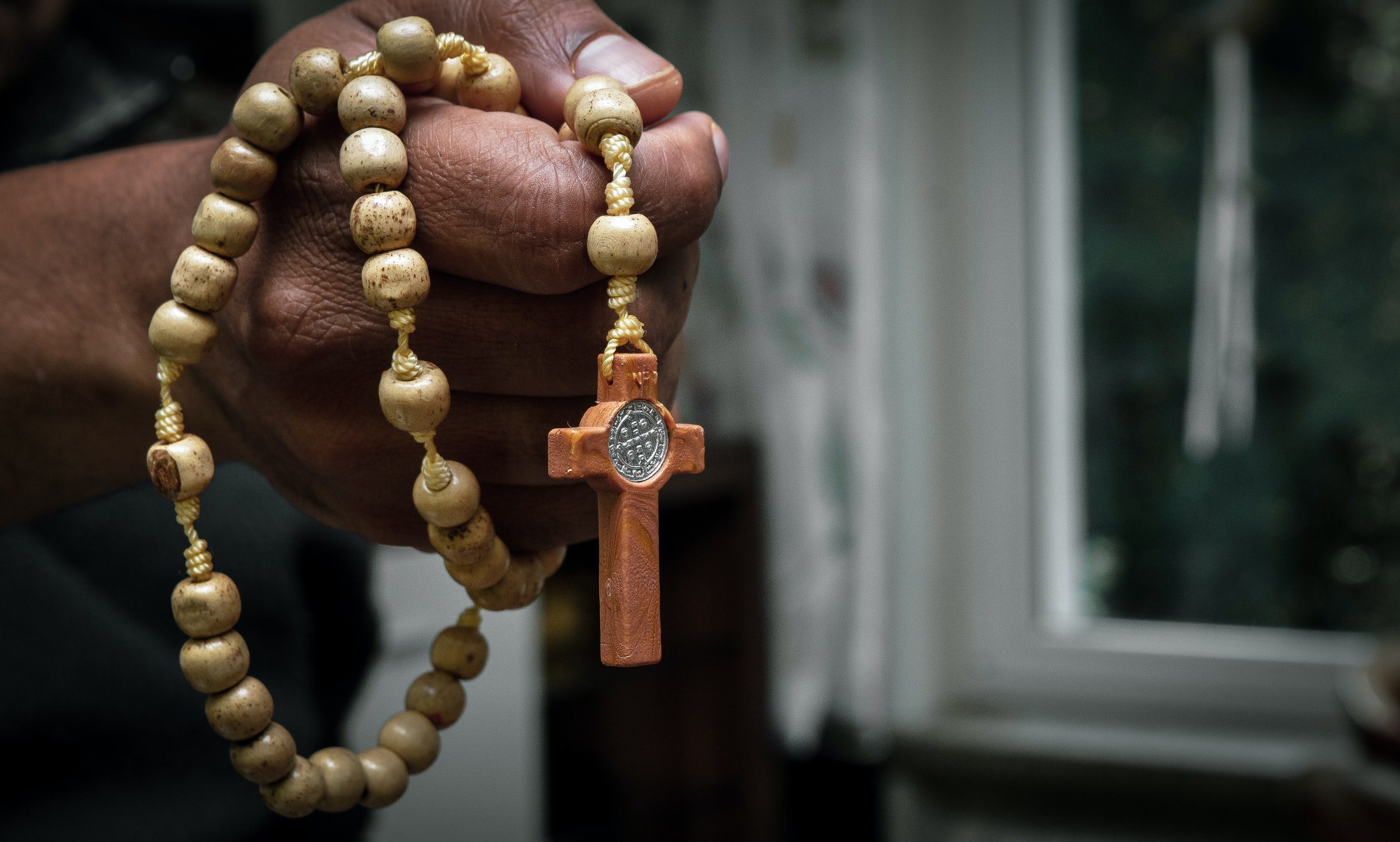 Hand holding wooden rosary